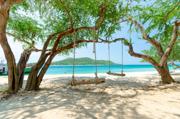 美丽宁静的海滩，树下木制秋千，光滑的沙滩和清澈的蓝色海水。夏季泰国海岸岛屿的度假背景。图片下载