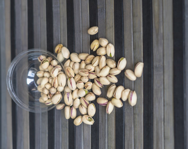 健康的食物背景图片近距离开心果。俯视图果仁开心果在杯盘上图片下载