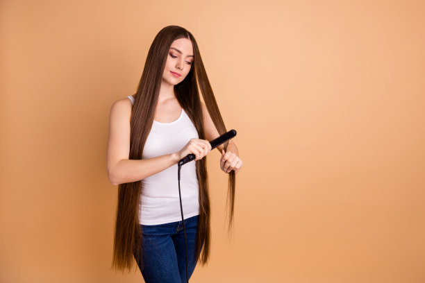 近距离的照片美丽的惊人的她，她女士的手臂，手握很长的头发，卷发，拉直，享受简单的过程，穿休闲的白色背心牛仔裤，牛仔孤立的柔和的米色背景图片下载