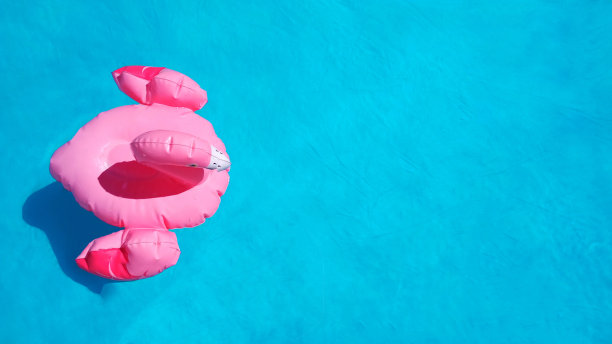 平躺充气粉红色火烈鸟游泳在清澈的蓝色水池水。夏日概念的茶点后的炎热。副本的空间。用于海报、横幅或传单。夏季新鲜销售理念图片下载