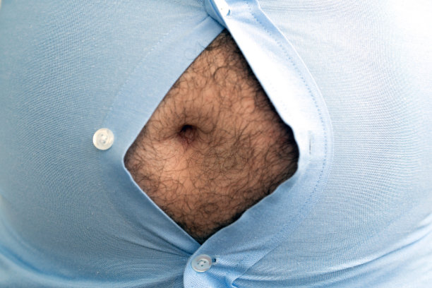 人超重。这张照片是啤酒肚、节食失败和吃错食物的象征。减肥的概念。紧的衬衫。图片下载