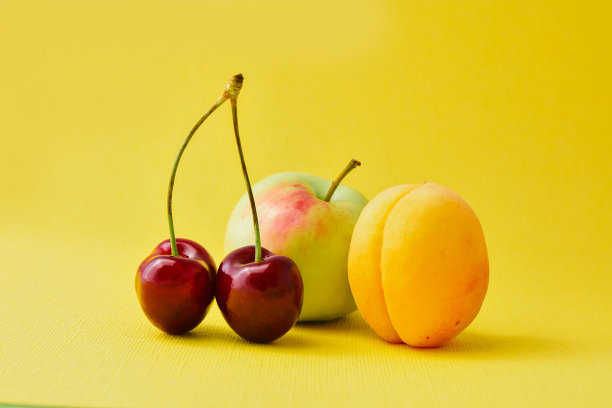 苹果，樱桃，杏子在黄色的背景上图片下载