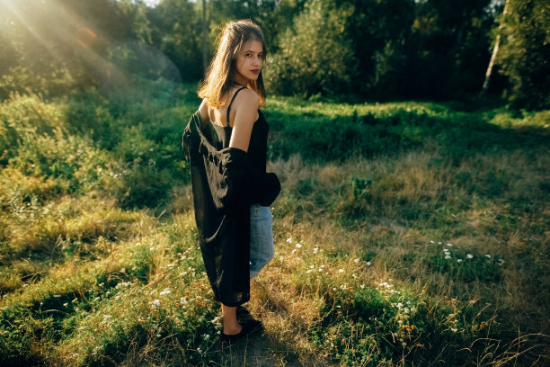 时髦的时髦女孩在阳光灿烂的公园摆姿势，令人惊叹的阳光光束，大气的时刻。时尚清凉的女人在晚上放松和微笑。有选择性的重点。复古的效果。创意图片图片下载