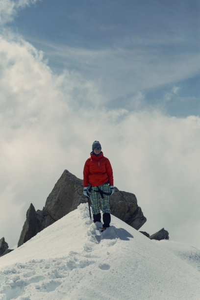 年轻女子站在积雪堆积的山脊上，向山顶升起图片下载