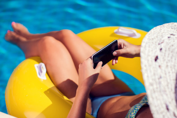 女人花时间和放松在游泳池与手机。人、夏、假概念图片下载