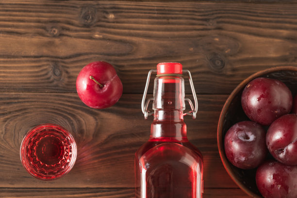 村里的桌子上放着一杯李子甜酒和李子浆果。平的。图片下载