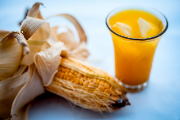 生的有机玉米芯或玉米粒与玉米粒汁一起单独放在装有冰块的玻璃杯中。图片下载