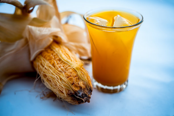 生的有机玉米芯或玉米粒与玉米粒汁一起单独放在装有冰块的玻璃杯中。图片下载