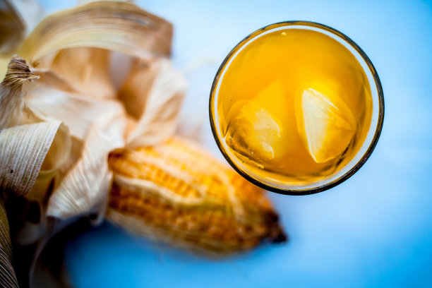 生的有机玉米芯或玉米粒与玉米粒汁一起单独放在装有冰块的玻璃杯中。图片下载