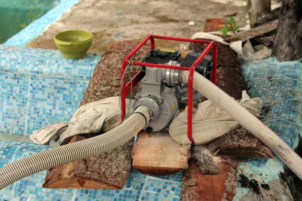 用工业水泵把洪水从被自然灾害破坏的家庭后院抽走，周围是木板和垃圾图片下载