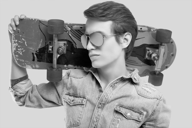 潮人戴墨镜和牛仔裤夹克与滑板摆姿势图片下载