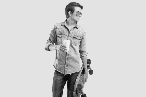 潮人戴墨镜和牛仔裤夹克与滑板和咖啡摆姿势图片下载