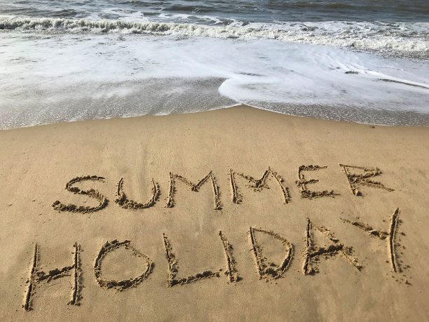 图片写在阳光明媚的海滩上，夏天的单词写在沙子上，用棍子，海浪，概念社交媒体上的照片手写字母在柔软的金色沙滩上，多塞特，英国海边的海岸线图片下载