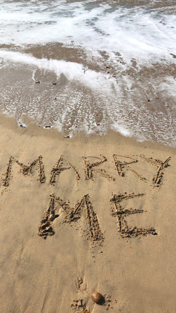 在阳光明媚的海滩上写“嫁给我”的文字，用木棍写在沙子上，海浪，概念社交媒体照片上的手写字母在柔软的金色沙滩上，多塞特，英国海边的海岸线图片下载