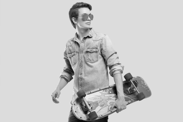 潮人戴墨镜和牛仔裤夹克与滑板摆姿势图片下载