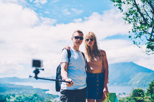 年轻的男女游客通过智能手机相机和单脚架自拍美丽的热带风景，相爱的情侣用手机拍摄夏季旅行的照片图片下载