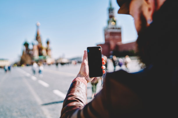 在探索莫斯科红场期间，男性旅行者用智能手机拍摄图片，空白屏幕为您的互联网内容或网站，技术和观光的概念图片下载