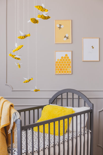 婴儿床上的黄色枕头、蜜蜂海报和幼儿房室内的挂饰。真实的照片图片下载
