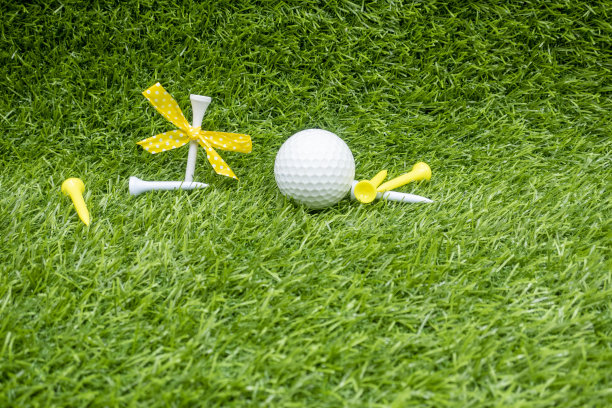 绿色草地上的带丝带的高尔夫球和球座图片下载