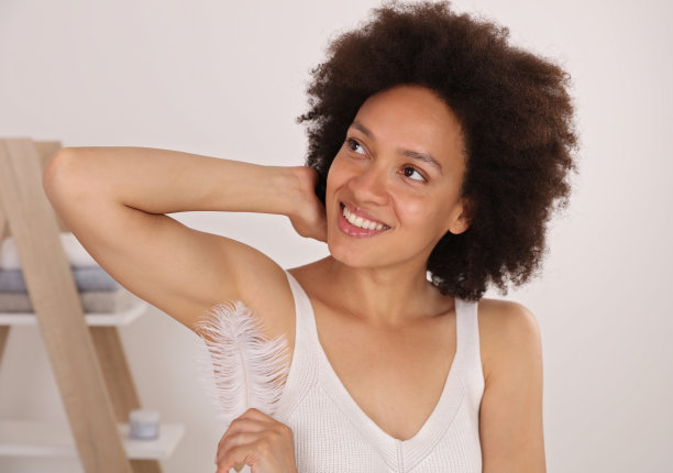 皮肤上有羽毛的漂亮女人。腋下脱毛，激光脱毛图片下载