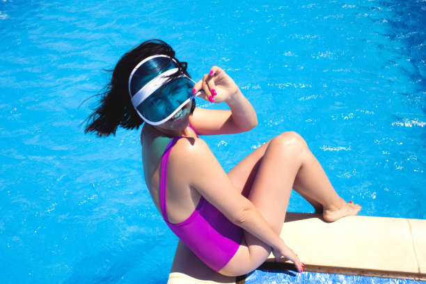 美丽和性感的女人放松在游泳池。图片下载