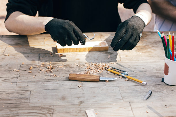 手用木头雕刻勺子，用凿子雕刻。木制车间。把木勺、木凿、铅笔、圆规、尺子和刨花放在肮脏的桌子上图片下载