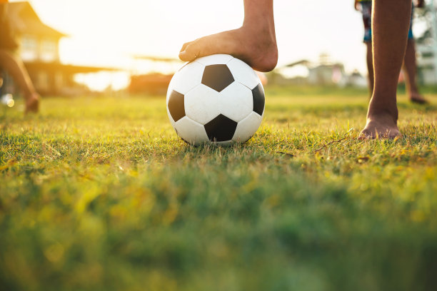 一群孩子在夕阳下在社区农村地区踢足球运动的运动图片。图片下载