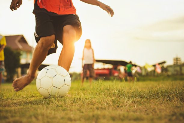 一群孩子在夕阳下在社区农村地区踢足球运动的运动图片。图片下载