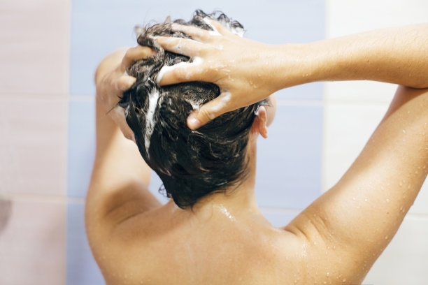年轻快乐的女人洗她的头发用洗发水，手与泡沫特写。美丽的黑发女孩正在洗澡，享受着放松的时光。身体和头发卫生，生活理念图片下载
