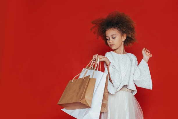 一个微笑着的漂亮女孩，一头卷发，穿着白色的衣服，在红色的背景下购物图片下载