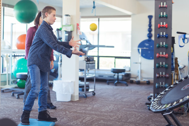 男孩在物理治疗诊所用蹦床做投掷练习图片下载