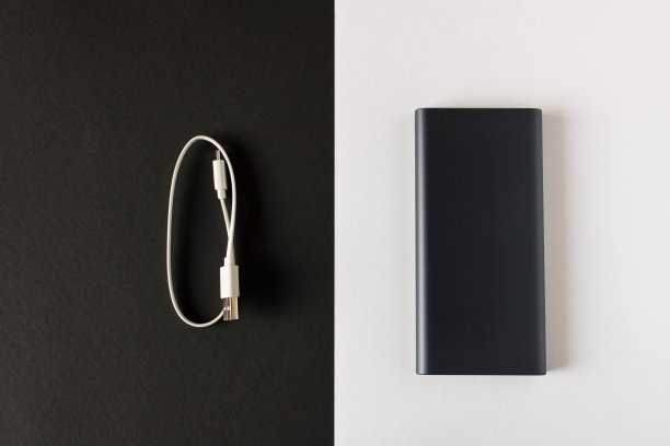 黑色电源银行与适配器为移动设备在黑白背景充电。图片下载
