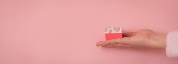 手拿一份礼物，粉红色背景，有拷贝空间图片下载