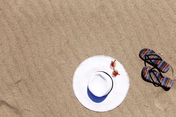 夏日度假海滩背景与人字拖在热带海滩上。拖鞋从沙滩上的沙子，放松的概念图片下载