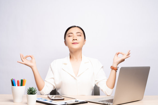 一个女人沉思着，在办公室孤立的背景下以瑜伽姿势握着她的手图片下载