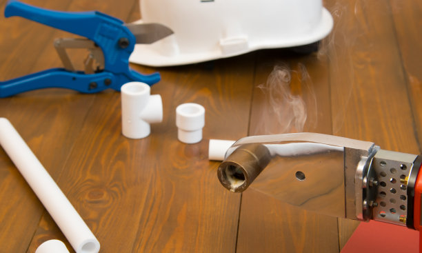 在一个深色的木制背景上，一个加热的烙铁焊接管，冒烟后与材料工作，特写图片下载