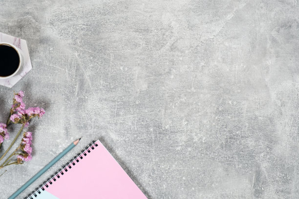 用咖啡杯，粉红色的干花，纸质的笔记本在混凝土表面进行简单的平铺组合。俯视图女性家庭办公室办公桌。美丽博客职场概念。时尚博客横幅英雄模型。图片下载