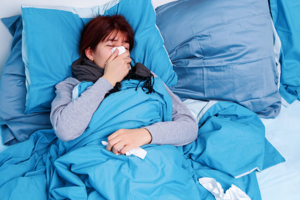 生病的黑发女人用纸巾擤鼻子的照片躺在床上图片下载