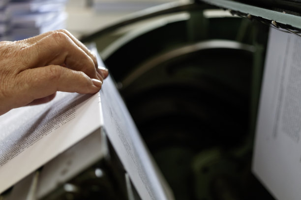 印刷用线钉书页的机器。用线缝书和笔记本的机器。女性在工作中。图片下载