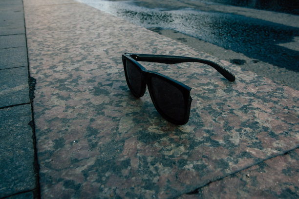 破碎的黑色太阳镜躺在人行道上，背对着城市风景图片下载