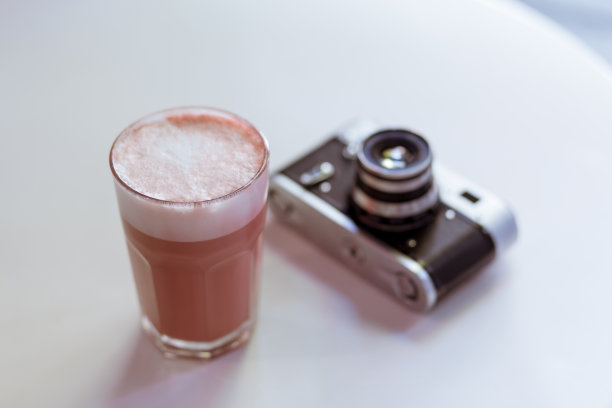 白色的桌子上放着粉色的时髦咖啡卡布奇诺，还有老式复古风格的胶卷相机图片下载