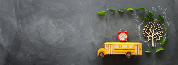 教育与返校理念。顶视图的照片，校车和闹钟在屋顶旁边的树与秋天的叶子在教室黑板的背景。俯视图，平放图片下载