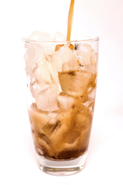 将可乐倒入玻璃杯中，气泡在白色背景上孤立的冰块上跳舞图片下载
