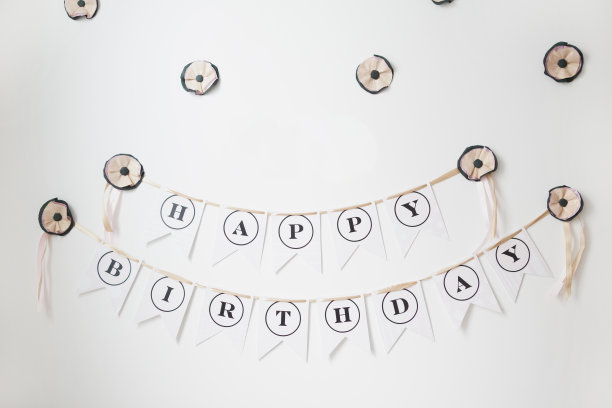 粉黑相间的花环挂在白墙上，还有纸花图片下载