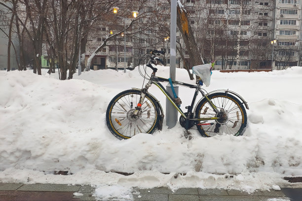 冬天，自行车在雪堆里。在柱子上，街道在雪中。前视图图片下载