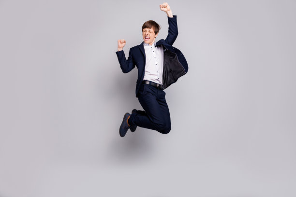 全身的身体尺寸的好看的欣喜若狂的孩子的照片，孩子举起拳头尖叫，喊，是的，有目标，成就穿着黑色的白色夹克，夹克，裤子孤立的灰色背景图片下载