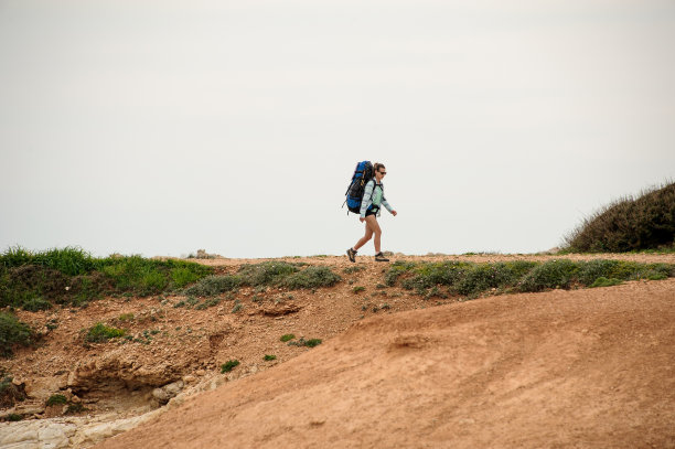 一个穿着衬衫戴着墨镜背着背包走在海边的女孩图片下载