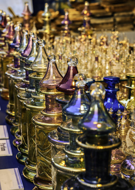 在落日的余晖中，几只装饰华丽、色彩斑斓的玻璃香水瓶紧挨在一起。图片下载