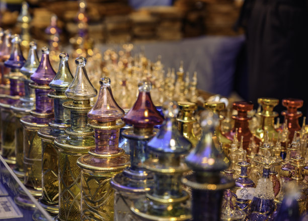 在落日的余晖中，几只装饰华丽、色彩斑斓的玻璃香水瓶紧挨在一起。图片下载