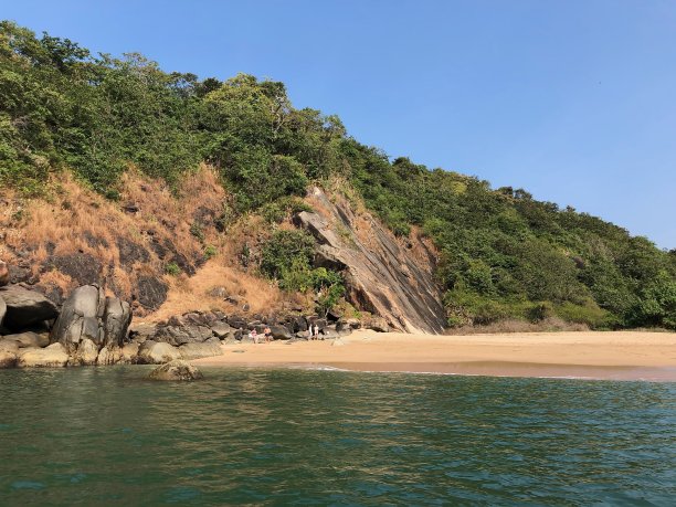 热带岛屿天堂的图像，蝴蝶海滩，Palolem，果阿，印度，棕榈树，私人附近的蜜月海滩与金色的沙子，温暖的绿松石海背景照片，岩石，悬崖面和游客度假图片下载